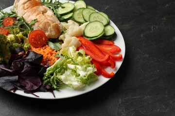 Balanced diet and healthy foods. Plate with different delicious products on black table, closeup. Space for text
