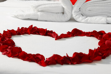 Fototapeta premium Honeymoon. Heart made with rose petals on bed, closeup