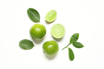 Whole and cut fresh ripe limes with green leaves on white background, flat lay