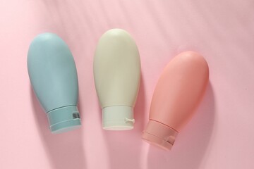 Cosmetic travel kit on pink background, top view