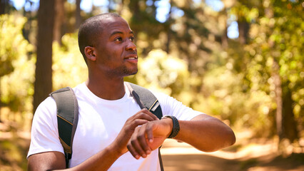 Young Active Man Checking Activity Monitor On Smart Watch Hiking Along Trail Through Countryside - 767220342