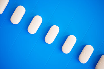 Symmetrical Arrangement of White Oval Pills on a Striking Blue Background
