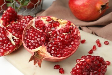 Piece of fresh pomegranate and seeds on white table, closeup
