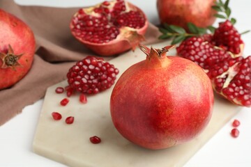 Fresh pomegranate and seeds on white table, closeup