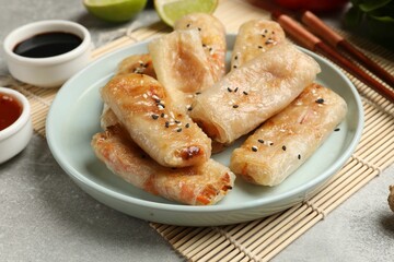 Tasty fried spring rolls served on gray table, closeup