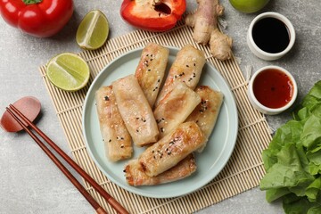 Tasty fried spring rolls served on gray table, flat lay