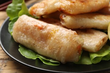 Tasty fried spring rolls and lettuce on table, closeup