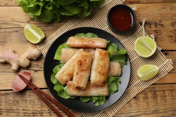 Tasty fried spring rolls served on wooden table, flat lay