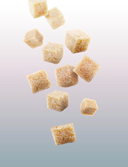 Brown cane sugar cubes falling on grey gradient background