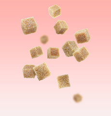 Brown cane sugar cubes falling on pink gradient background