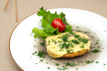 Baked potatoes with cheese and herbs on a plate