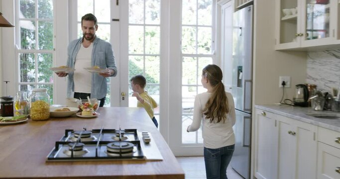 Father, children and breakfast in kitchen for morning nutrition, pancakes or connection. Man, son and daughter for hungry meal together at table for weekend family relax for holiday, vacation or love