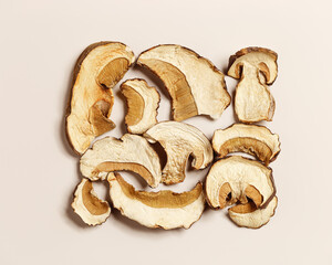 Dry slices of porcini as creative pattern, dehydrated food boletus mushrooms, top view, flat lay, beige background, minimal style. Natural food ingredient forest white mushroom, healthy eating