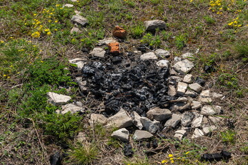 Naklejka na ściany i meble Abandoned extinct stone hearth for bonfire. Survival in wild. Protecting forest from spread of fire
