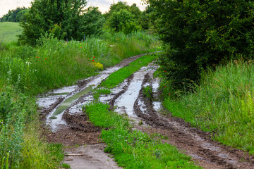 Fototapeta na wymiar dirty broken rural road with deep tire tracks