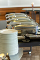 Stack of plates next to closed chafing dishes