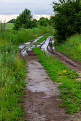 Fototapeta na wymiar Broken country dirt road in spring mountains with lots of muddy puddles after the rain