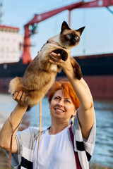 Woman holds a Mekong Bobtail cat above her head