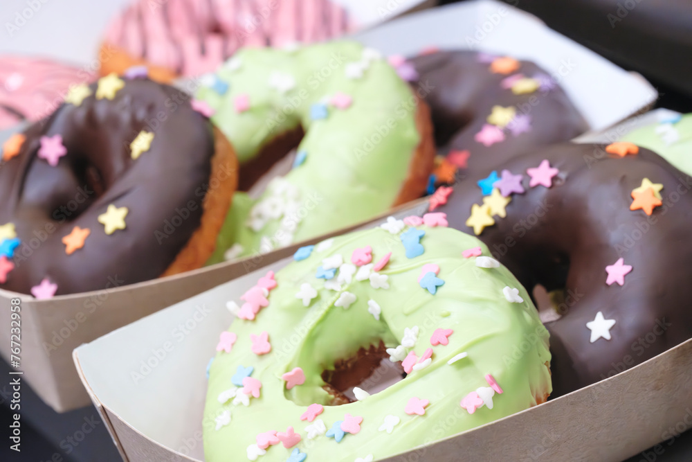Leinwandbilder a tray of donuts with pink frosting and chocolate sprinkles. the donuts are arranged in a row and ar