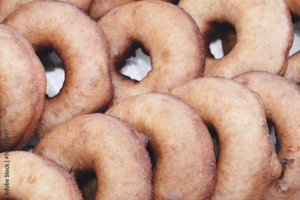 Poster A stack of donuts with a brown glaze. The donuts are piled on top of each other, creating a visually appealing and appetizing display