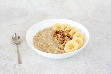 a bowl of oatmeal with bananas and a spoon next to it