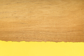 Piece of yellow torn paper on a wooden background. Space for text.