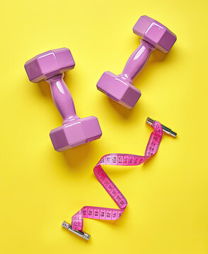 Two purple dumbbells and a pink tape measure on a yellow background, in the style of minimalism