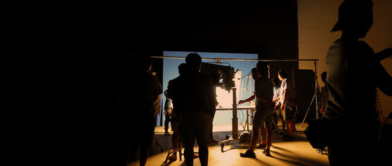 Silhouette images of video production behind the scenes of making of TV commercial movie shoot that film crew team lightman and camera man working together with director and equipment in big studio. - obrazy, fototapety, plakaty