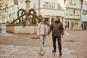 Obraz premium Loving couple of tourists walking around old town. Couple of lovers leisurely stroll in the cool autumn morning on the streets of a BIETIGHEIM-BISSINGEN (Germany). The guy holds his wife. Vacation
