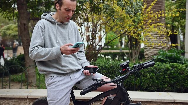 Young adult hipster man renting an electric bike using a rental app on mobile phone. Bike sharing city service. Paid rent of electric scooter. Using smartphone to rent and pay for public eco transport