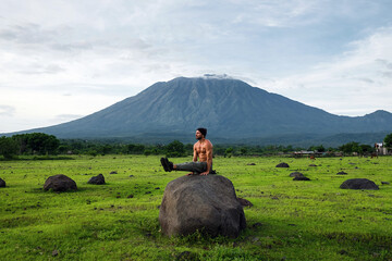 A male yogi, with a naked torso, is engaged in morning yoga practice in nature, with a gorgeous...