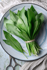 Top view on bunch of fresh bear's wild garlic leaves on plate close up. Food photography - 767269544