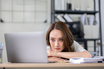 Businesswoman looks stressed, bored and holding her head. Indicates a headache while working at a...
