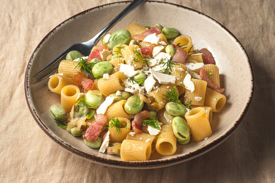 Sicilian traditional pasta with fave beans, green onions, pancetta, wild fennel and  ricotta salata  (salt ricotta). Poor cuisine, la cucina povera of Sicily.. Spring, Easter recipes, front view