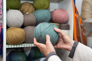 Female hands holding a ball of wool inside a store. 