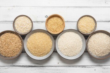 Various types rice in bowls, white wooden background. Top view, flat lay. - 767283104