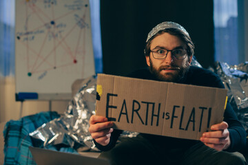 Championing Pseudoscience: Man Holding 'The Earth is Flat' Sign - obrazy, fototapety, plakaty
