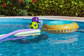 Yellow pool float, pool inflatable ring and balls float in the pool. Swimming pool safety