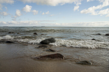 Fale rozbijające się o kamienie na piaszczystym brzegu © Sebastian