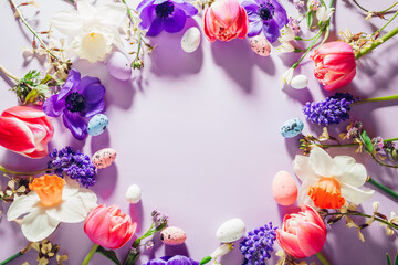 Happy Easter mockup. Easter eggs background with spring pink purple flowers flat lay, empty center. Greeting card banner