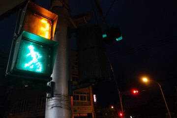 A captivating night scene showcasing a pedestrian traffic light glowing in vibrant green, with an...