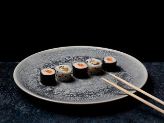 sushi preparado sobre hojas plato y pizarra con fondo negro
