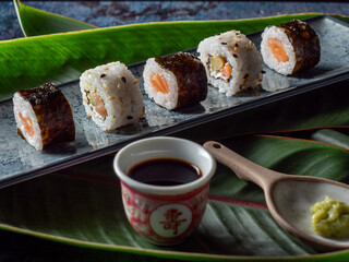 sushi preparado sobre hojas plato y pizarra con fondo negro