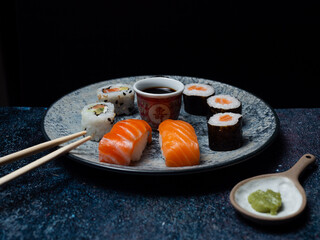 sushi preparado sobre hojas plato y pizarra con fondo negro