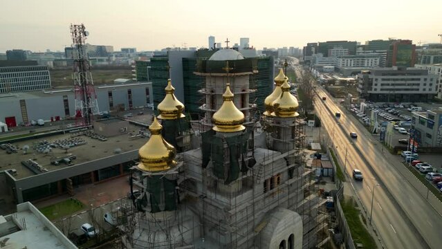 Aerial close up drone shot of the construction of an orthodox church with golden domes. Scaffold work on a brand new place of worship. gilded bell tower.