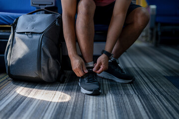 Traveler Tying Shoelaces Beside Luggage on Floor