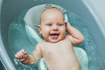 Bathing a baby in a bathtub on a stand. Baby's first bath at home after birth.