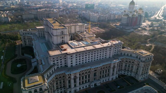High angle drone footage of the Palace of the parliament in Bucharest Romania. Constitution Square seen from above on a sunny green day. Ceausescu's palace seen from above. Flyover shot
