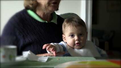 Casual candid authentic grand-son baby with grand-mother at lunch table