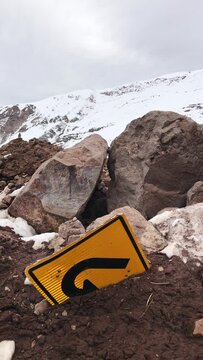 A turn in the cold: a solitary "u turn" sign lost in the snow and rocks of a snowed mountain peak